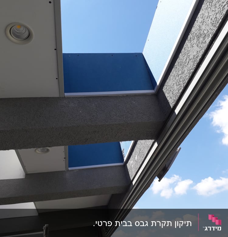 קיר גבס אפור עם לוח כחול ותאורה שקועה